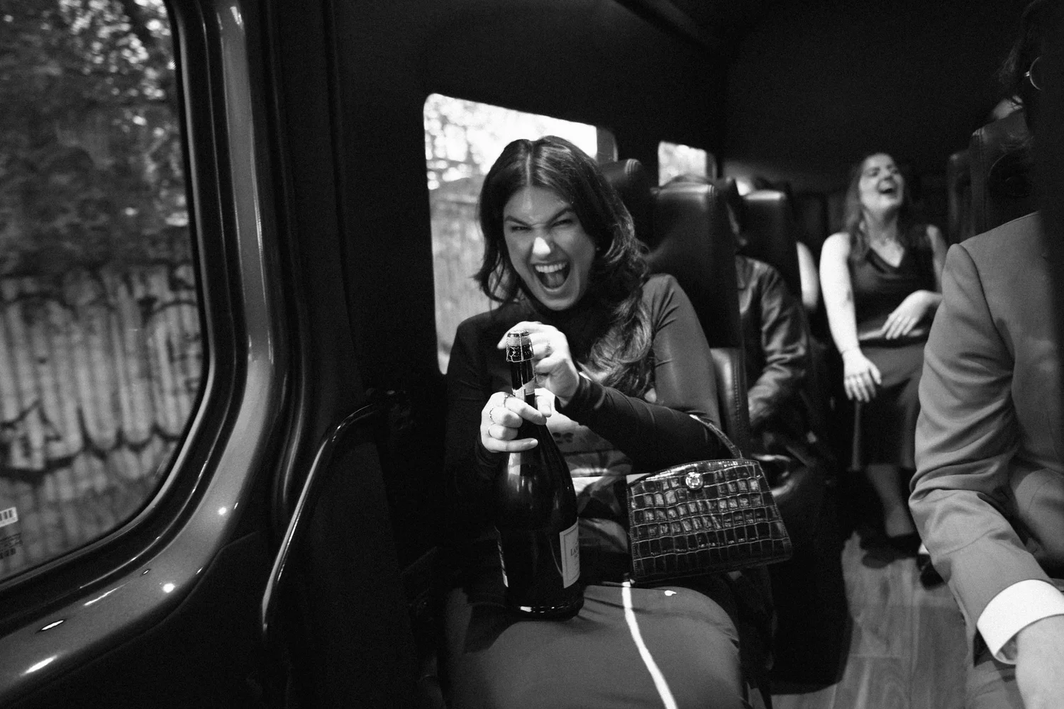 Bridesmaid pops champagne on the party bus