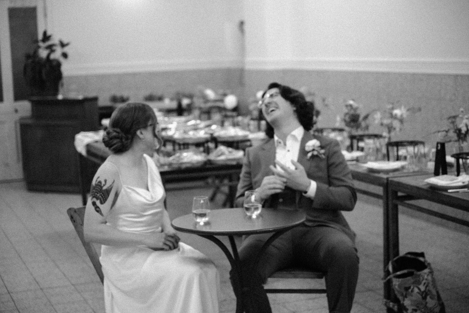 Groom laughs with the bride at a cafe table in the dining room