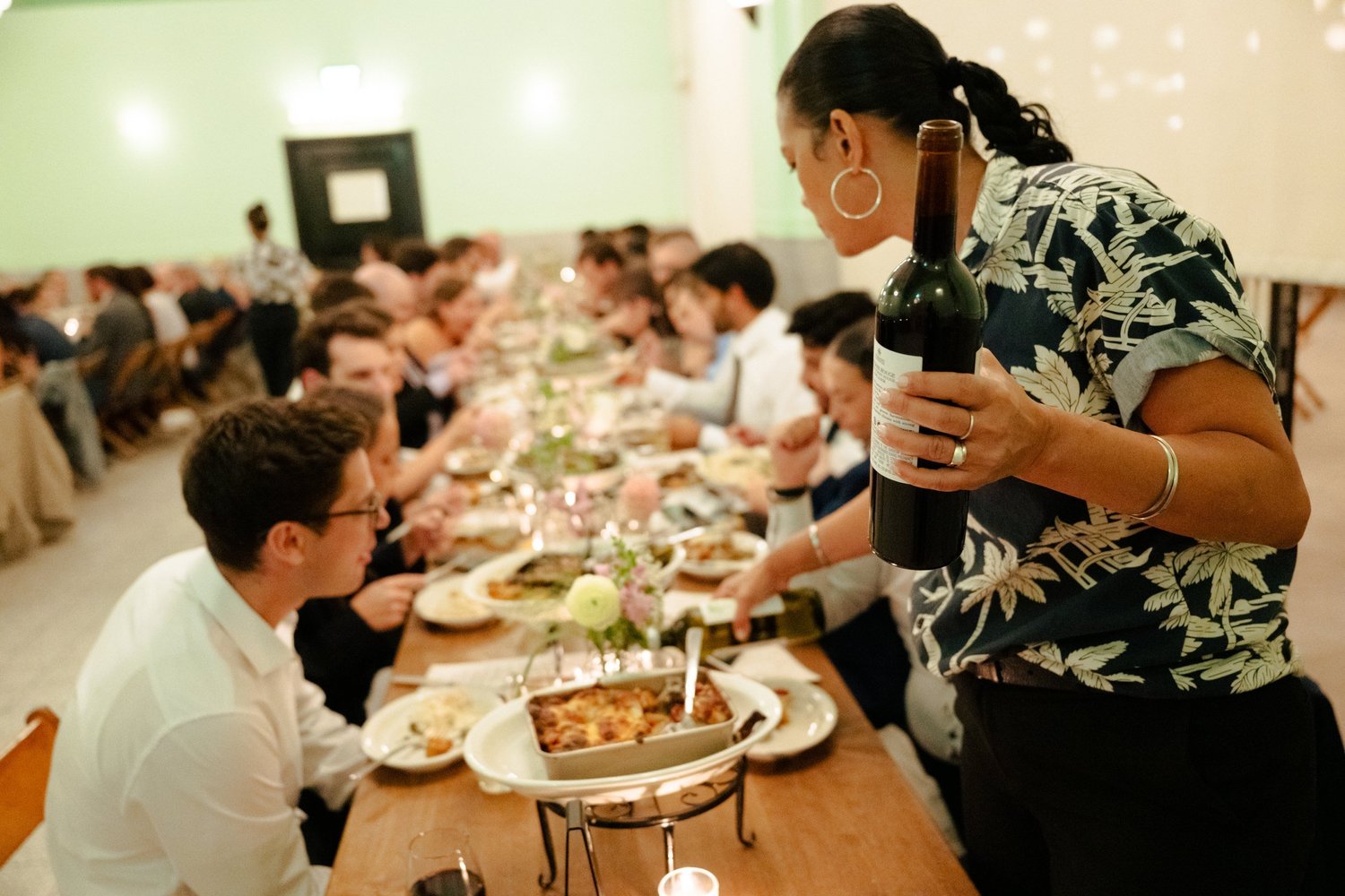 Server pours wine down a long table in the mint green Neptune Room