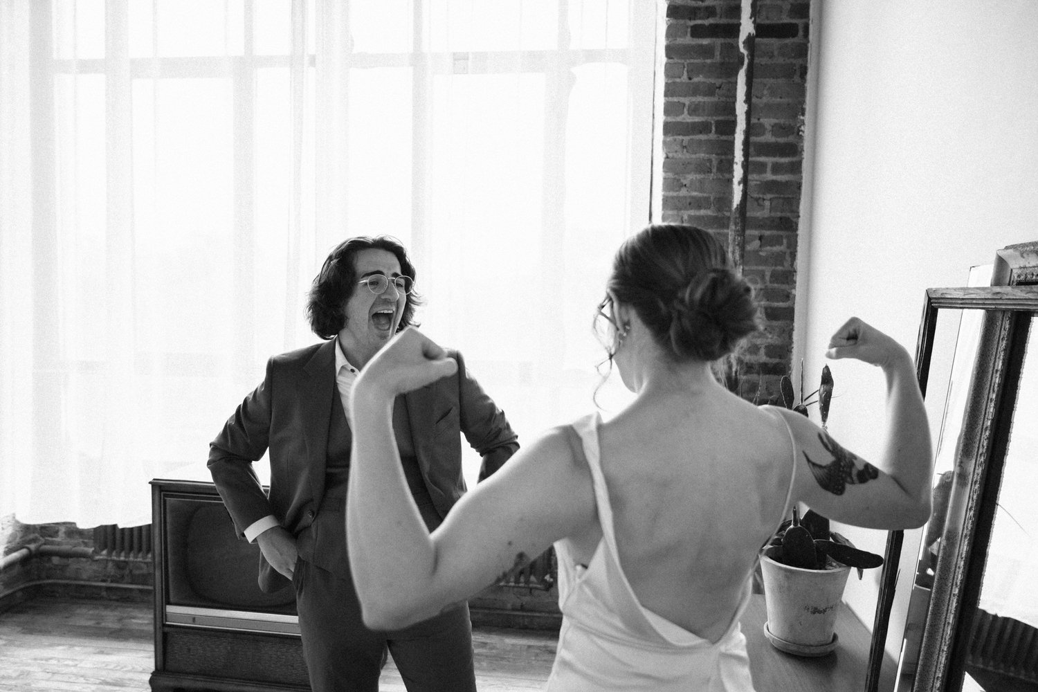 Bride flexes for the groom during their first look in a Brooklyn loft