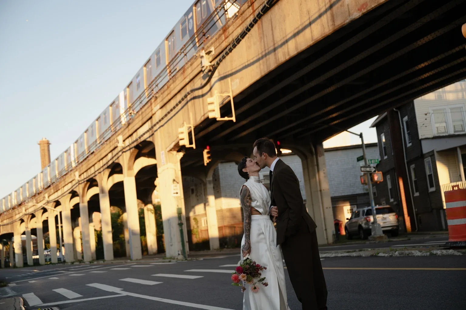 A wedding couple kissing beneath the elevated tracks in Brooklyn