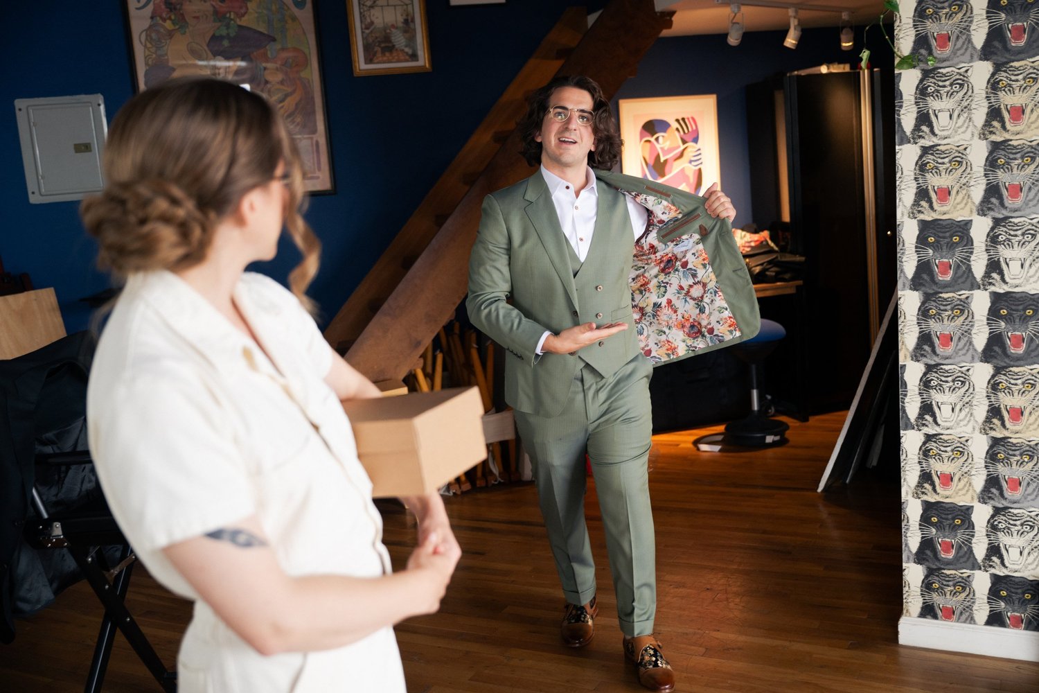 Groom shows off the floral lining of his sage suit while getting ready