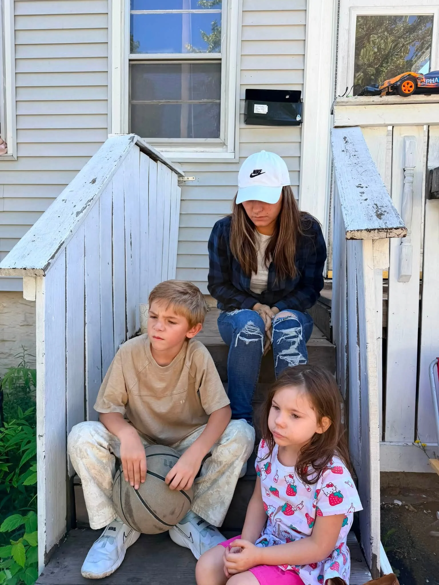Original porch snapshot 1: three people seated on the front steps