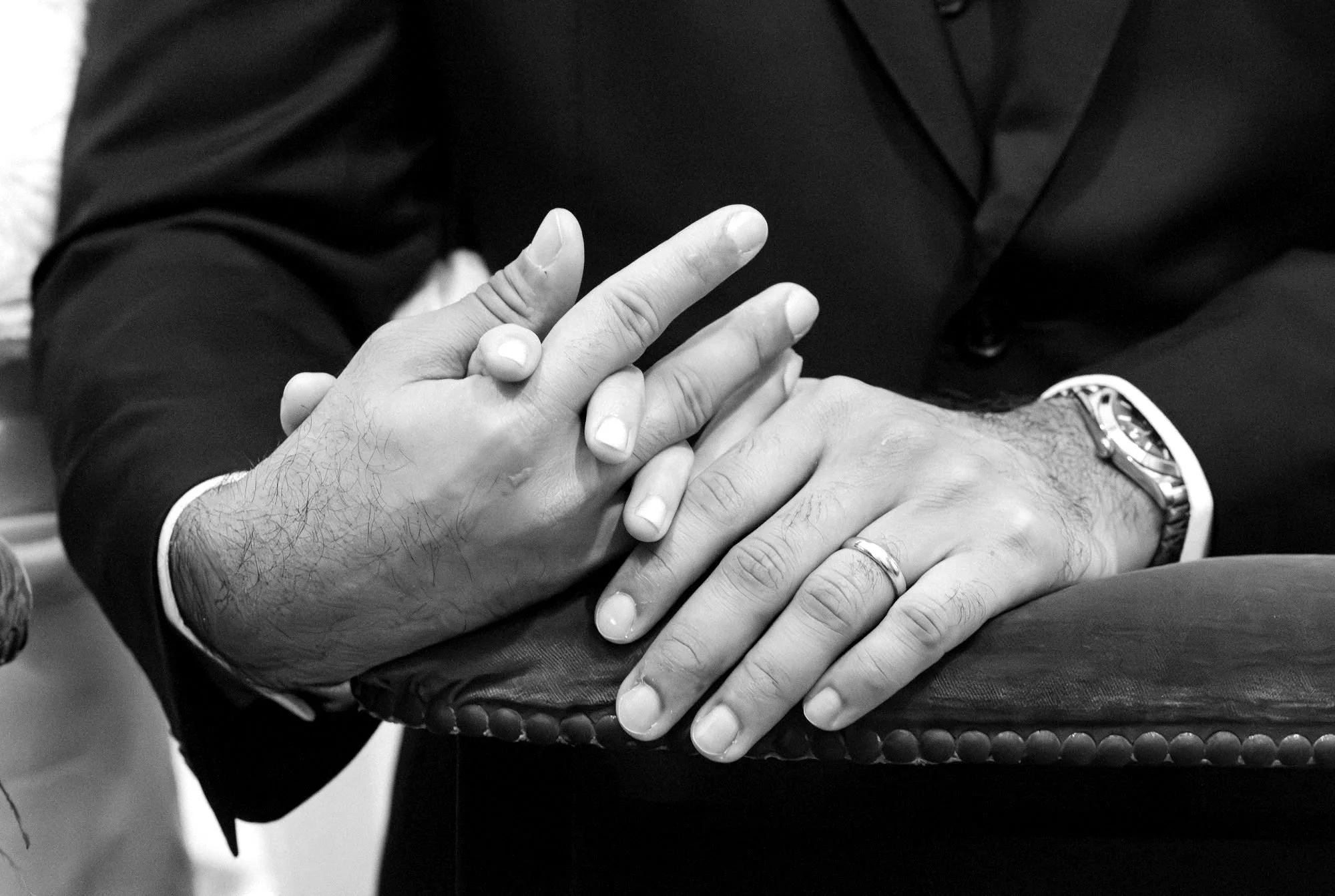 Las manos de los novios entrelazadas sobre el reclinatorio