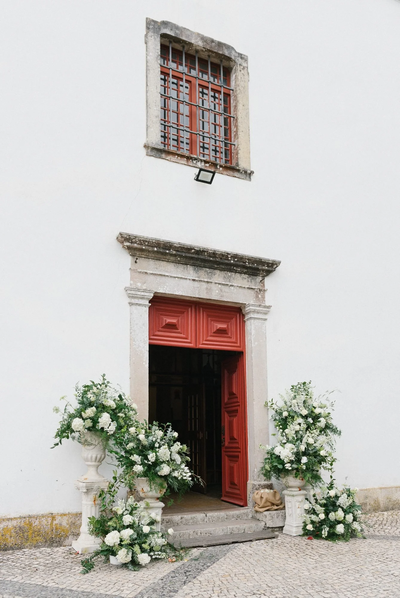 Fachada blanca de la iglesia de Colares con flores en la puerta