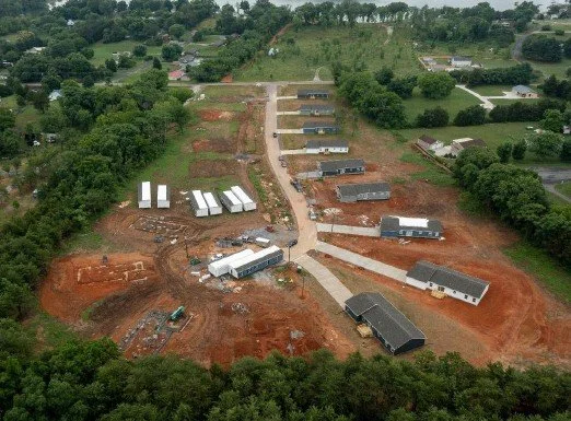 Aerial view of an active development site with roads, sitework and homes under construction