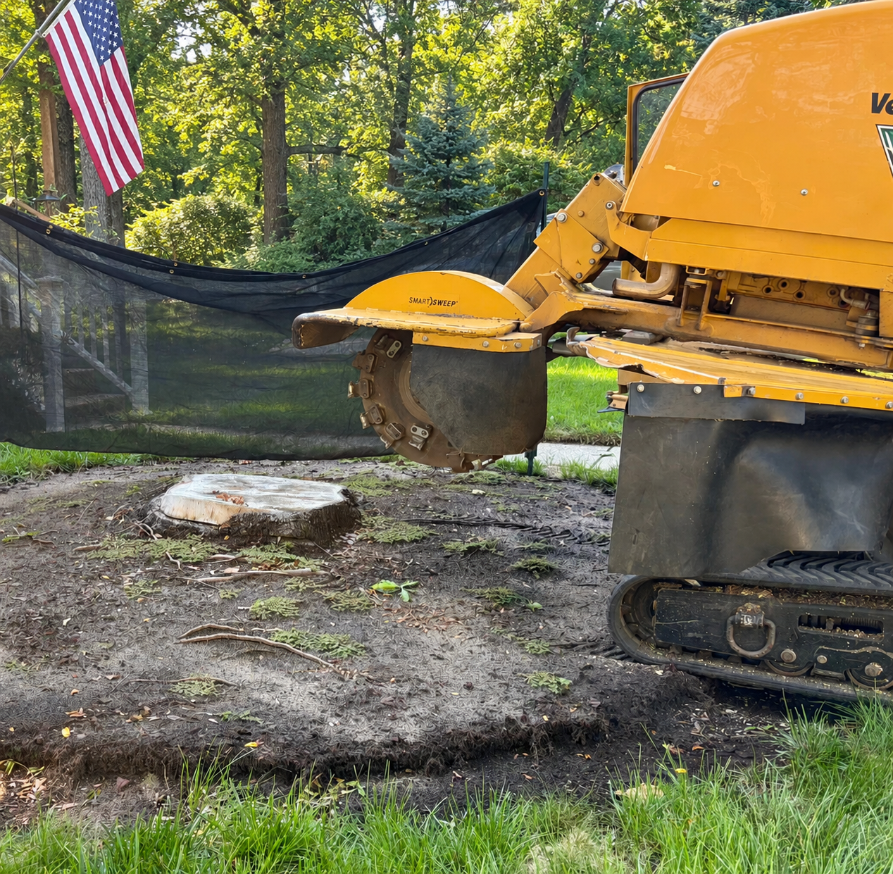 Vermeer SC70TX tracked stump grinder with SmartSweep cutting wheel grinding a large stump below grade