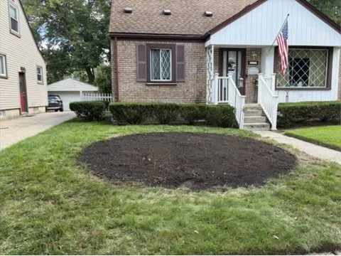 Fresh screened topsoil graded flat where a stump was removed in a Clawson MI front lawn