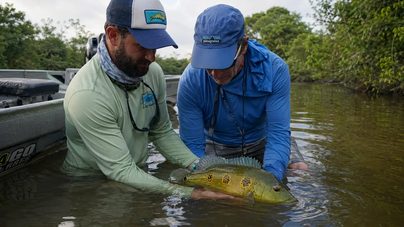 Fly fishing guide helping a client handle a fish during a real landing moment