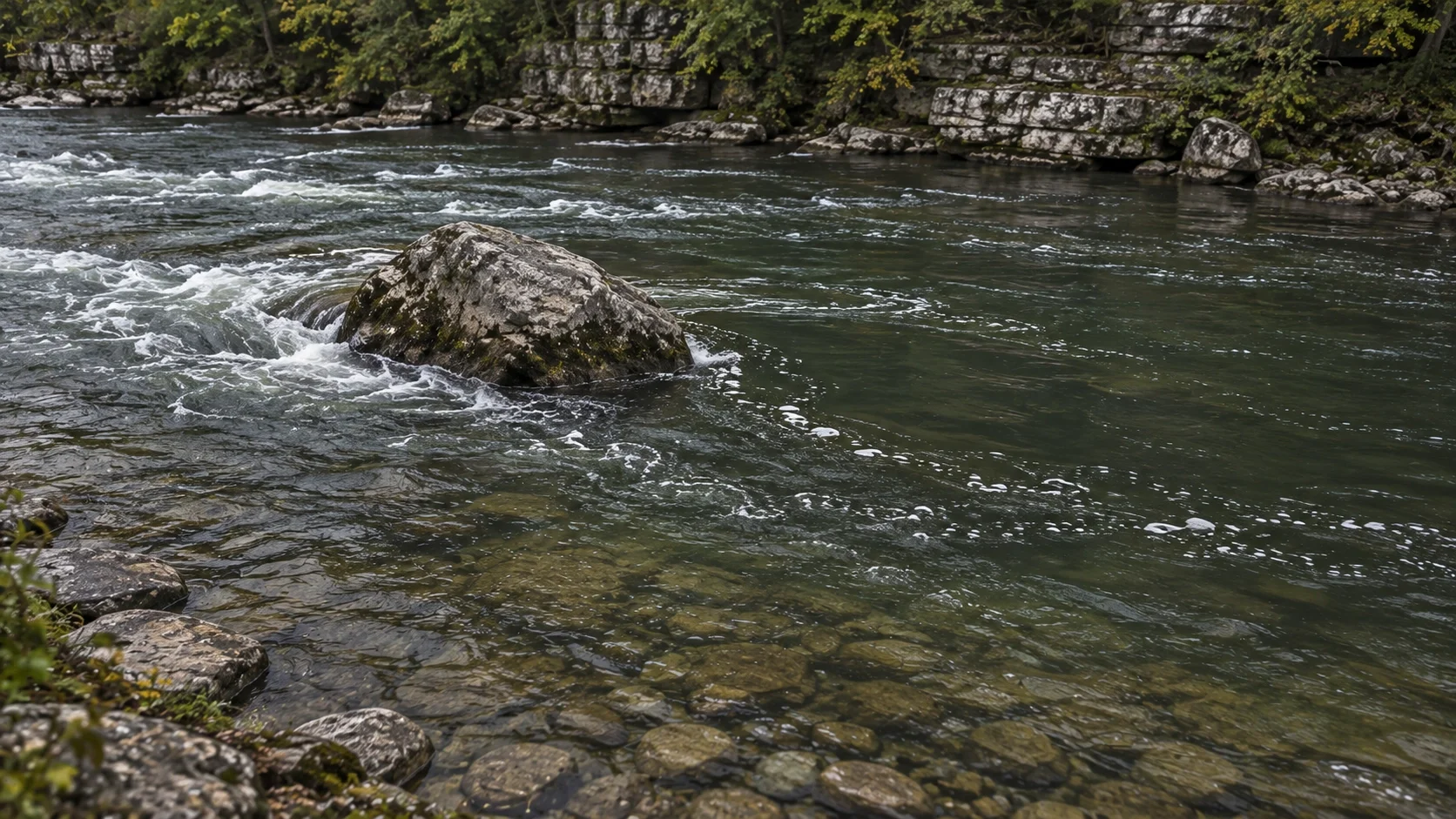 A current seam and slack eddy below a boulder where river smallmouth hold