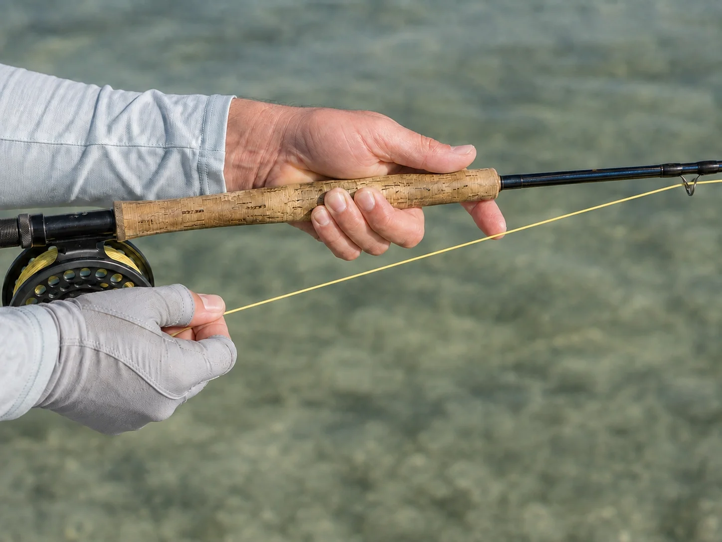 Close-up of fly angler hands demonstrating the strip set, stripping hand pulling line while rod stays low