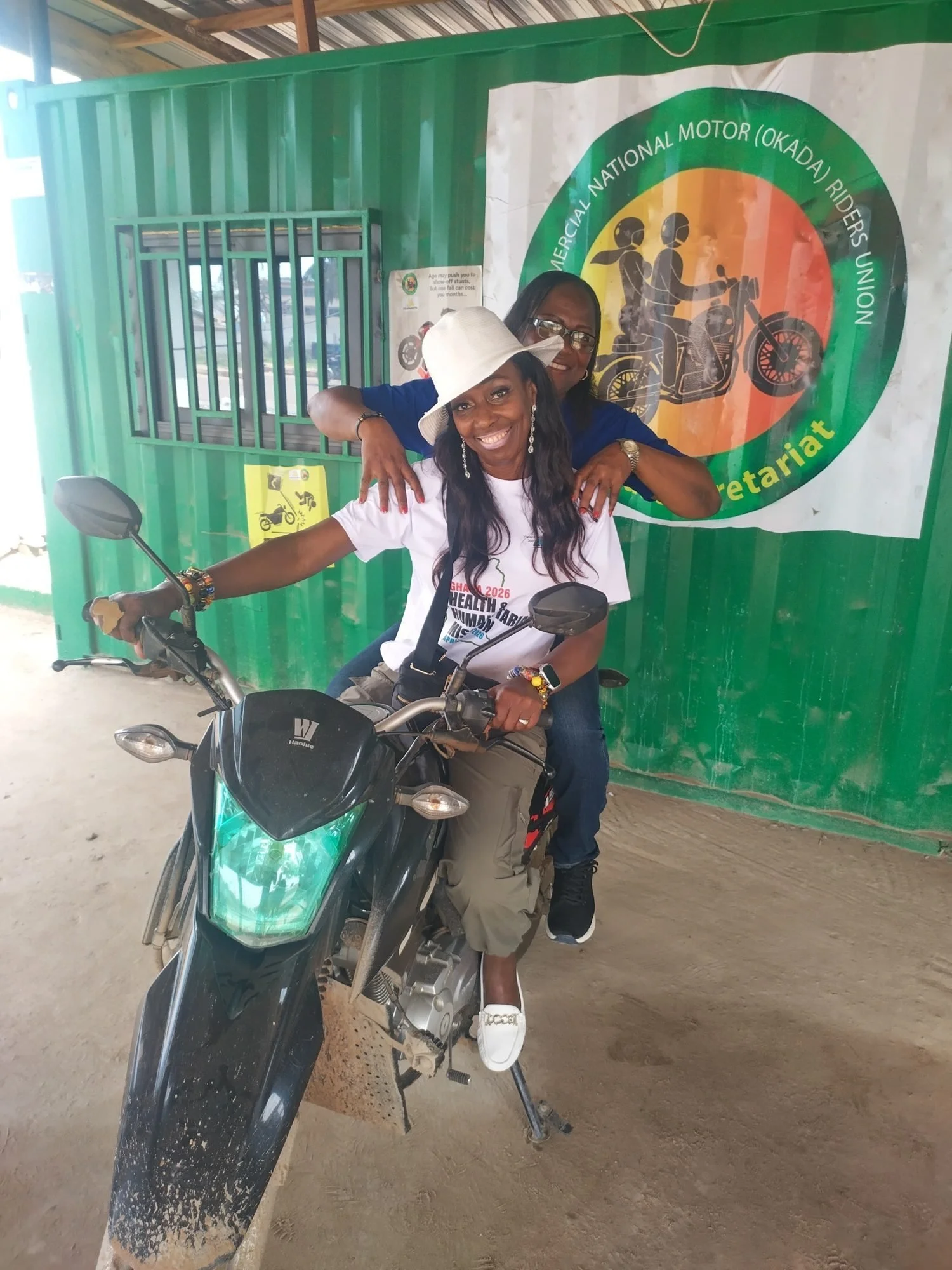 Nana Noi on a motorbike in Ghana, wearing a safety helmet