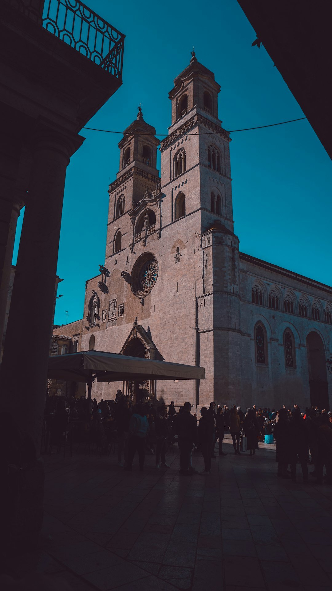 Altamura Cathedral rises above a narrow street filled with people.