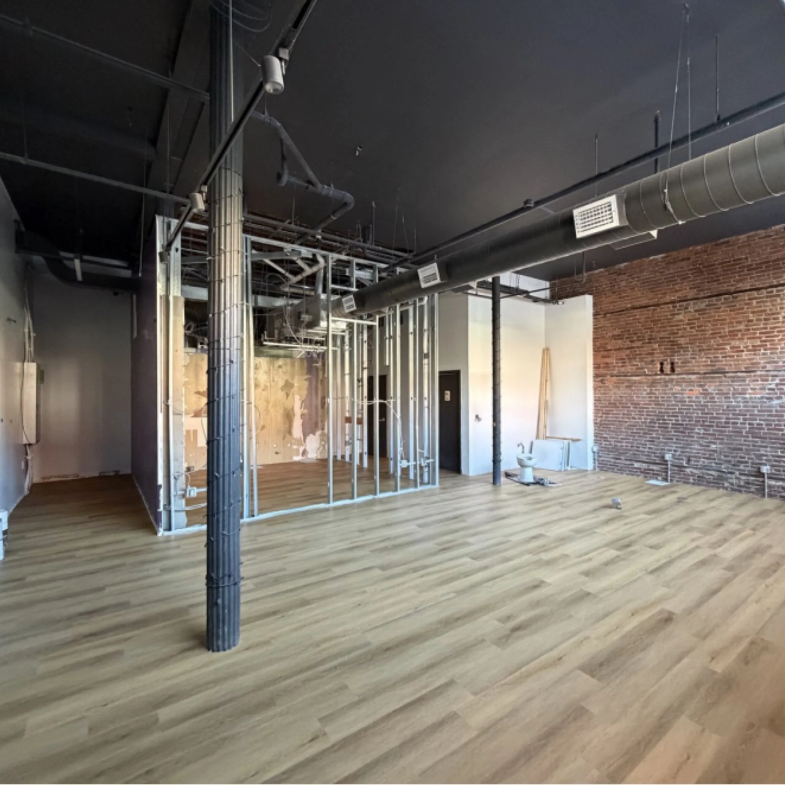 Inside Suite Retail 1 — exposed brick, hardwood, 16-foot ceilings