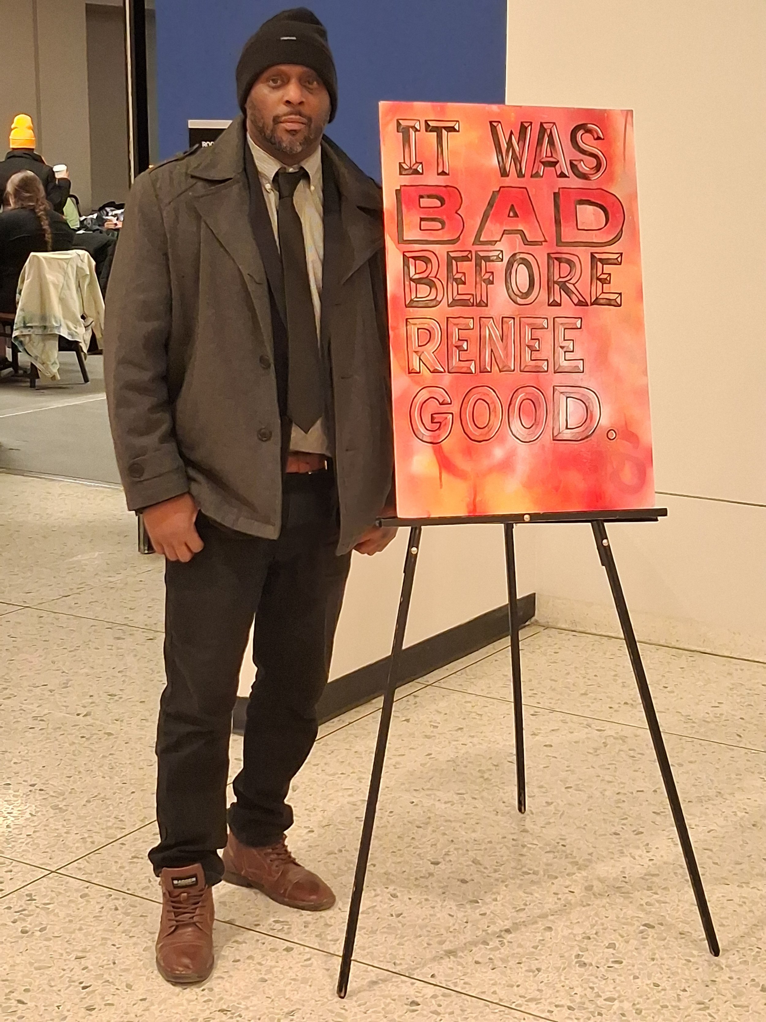 Thomas Kearney stands beside an advocacy sign in Albany.