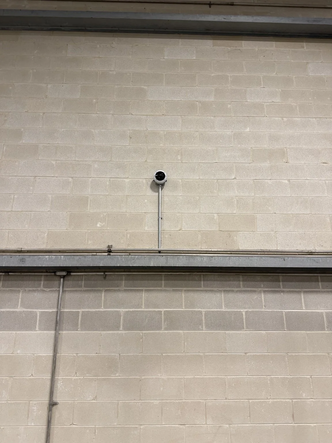 Axis security camera installed on a masonry wall with metal conduit