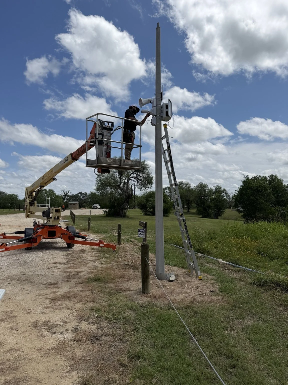 Technician working from a boom lift on a pole-mounted security installation