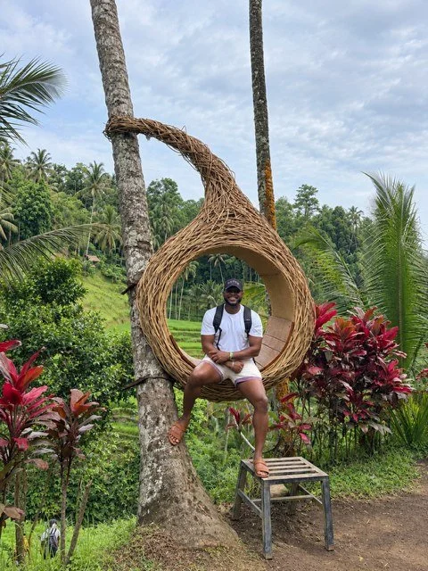 Mike Randle sitting in a woven jungle swing among palm trees