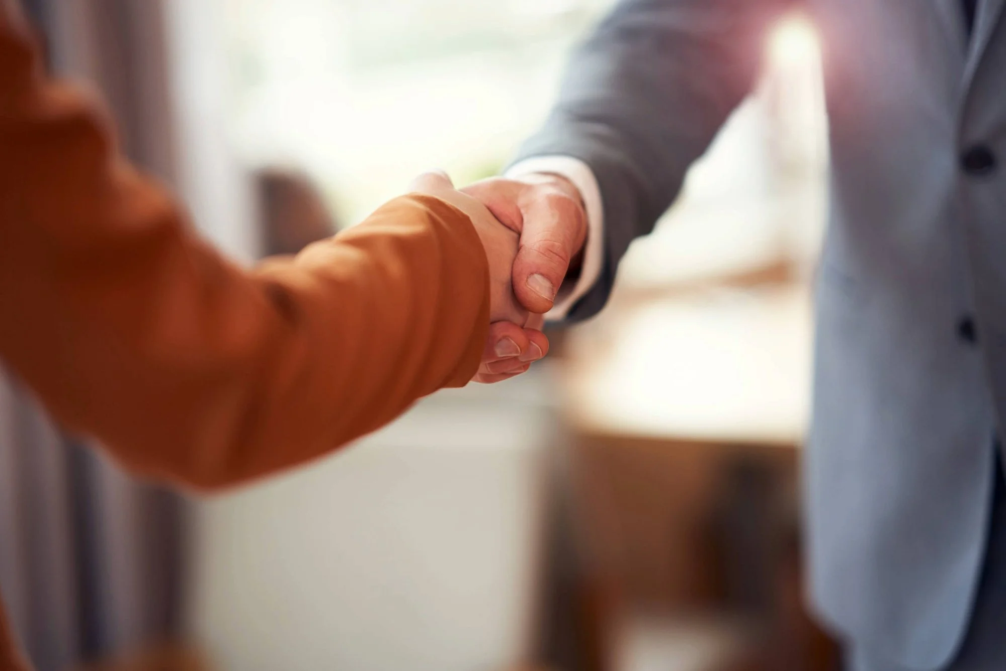 Close-up of two people shaking hands in a professional setting.
