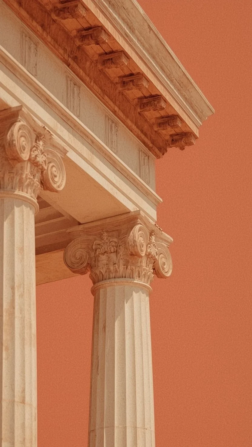 Detail of classical Ionic columns and ornate cornice against a warm sky.
