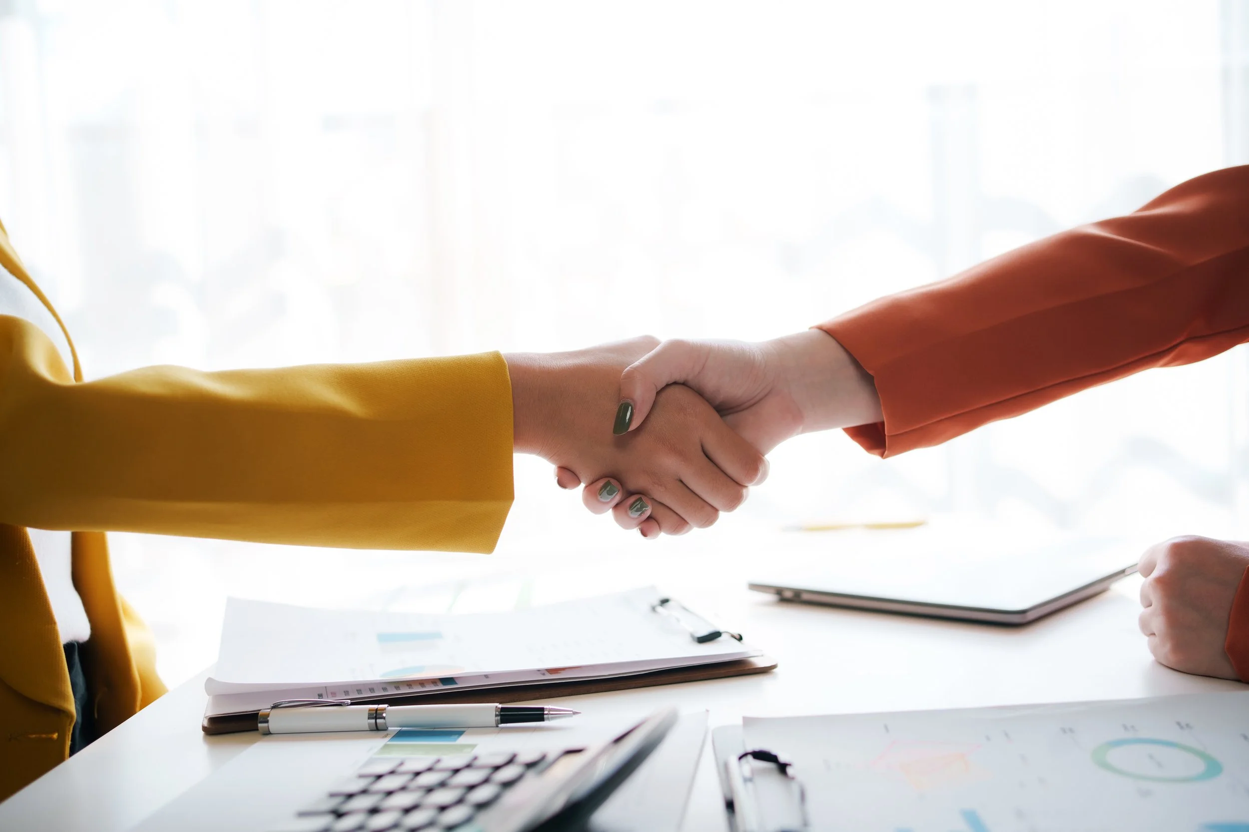 Close-up of two people shaking hands in a professional setting.
