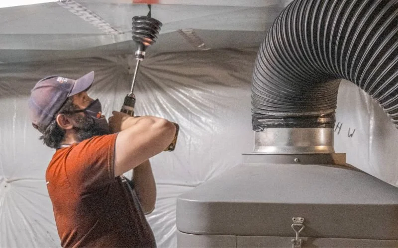 Licensed and trained HVAC technician drilling into main duct for duct cleaning services