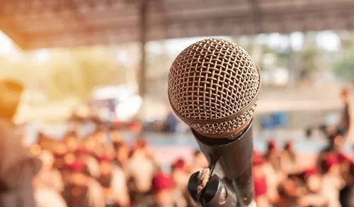 Microphone on stage facing a blurred audience, representing public speaking anxiety