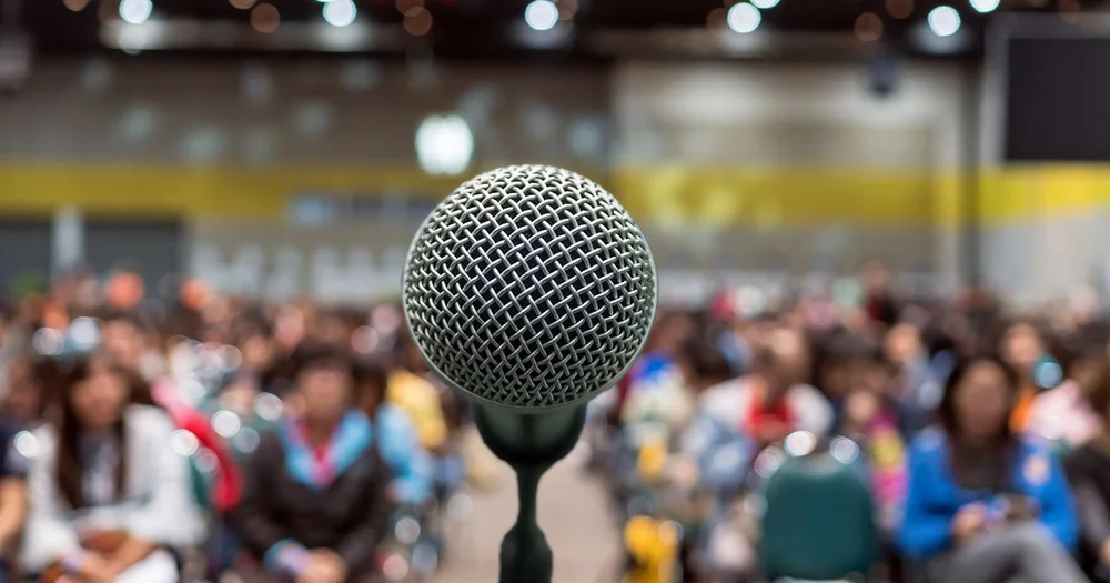 Microphone on stage facing a large audience, representing performance anxiety and public speaking hypnotherapy in Orlando