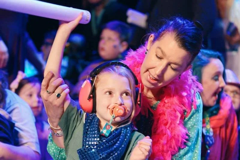 A happy child waves a toy in the air on stage at The Dome in Brighton