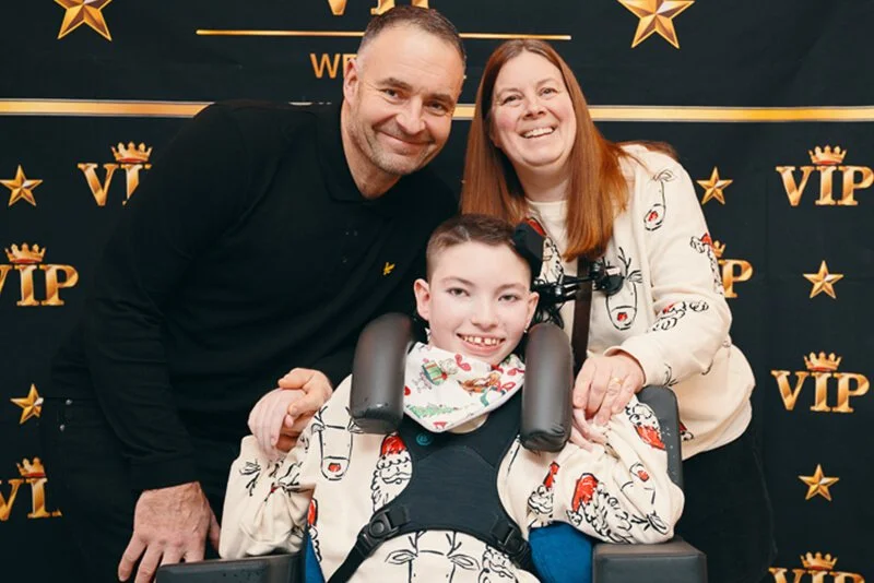 Santa Claus waving while families enjoy festive decorations and music
