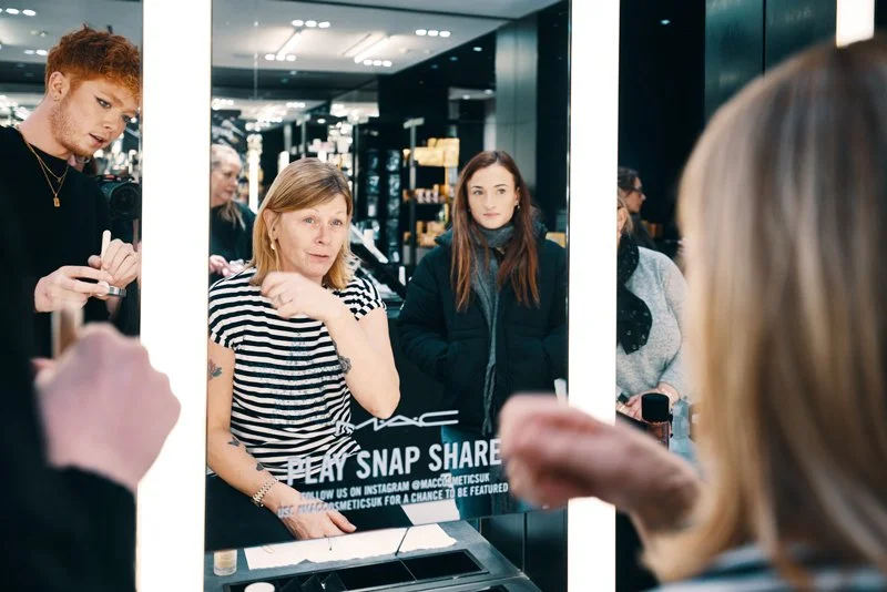 Two women smiling in a mirror while enjoying pamper treatments