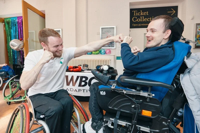 A young man wearing boxing gloves takes part in an adaptive boxing activity