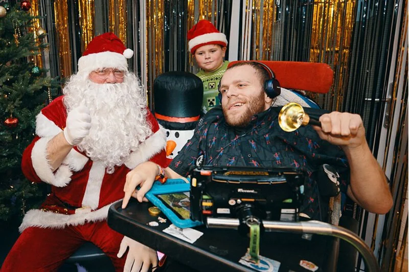 Santa Claus sitting with children holding wrapped presents at the event