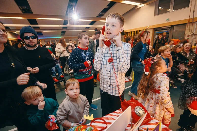 Excited children smiling as Santa hands out presents at the Christmas event