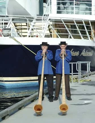 Two Swiss alphorns welcoming guests before the boat cruise