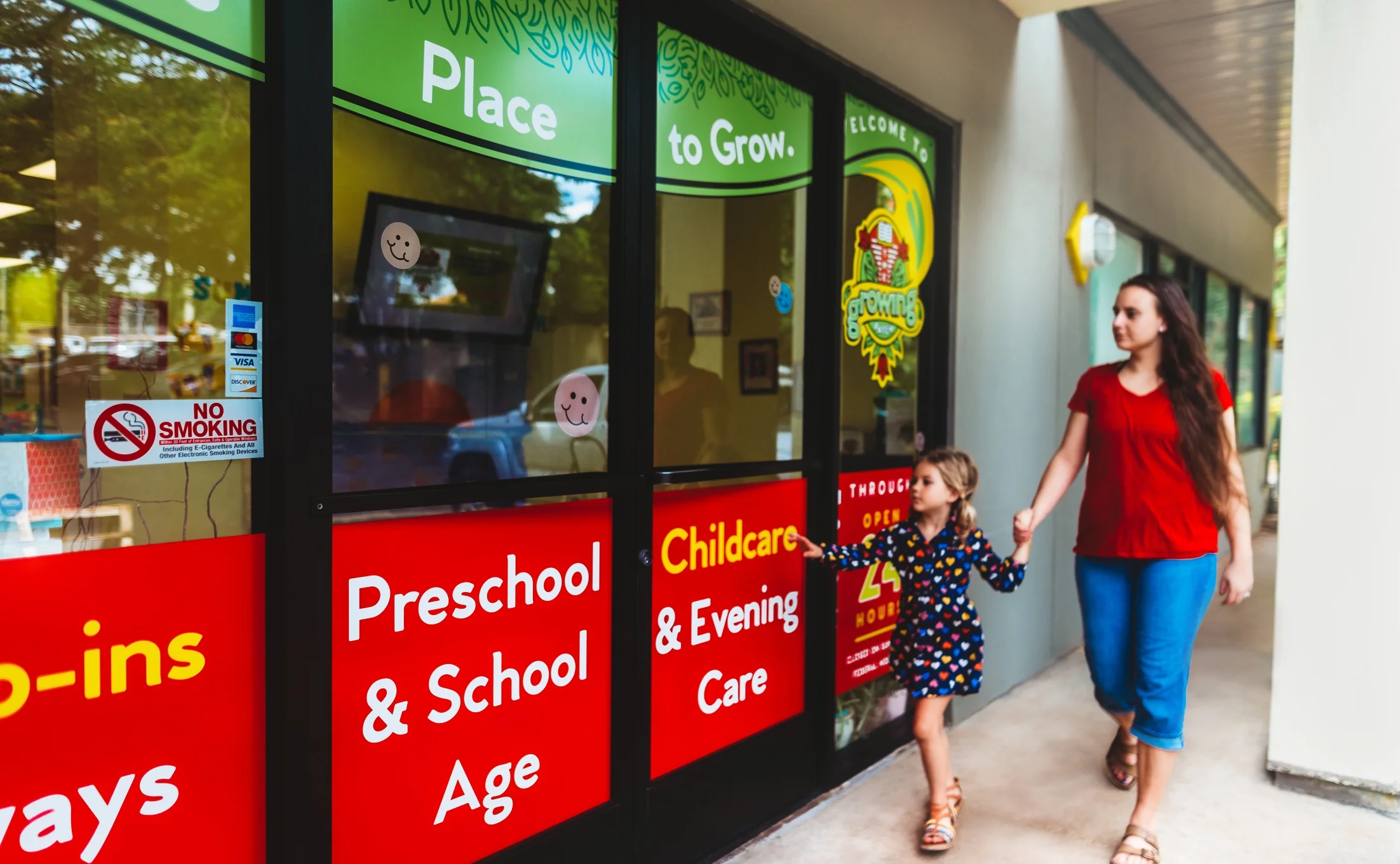 Mother and daughter walking hand in hand past The Growing Patch storefront