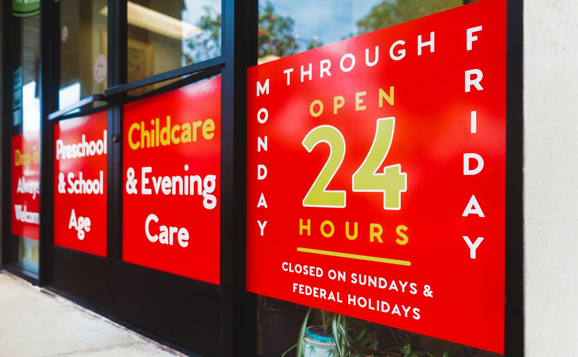 Close-up of The Growing Patch storefront window panels listing hours and childcare services