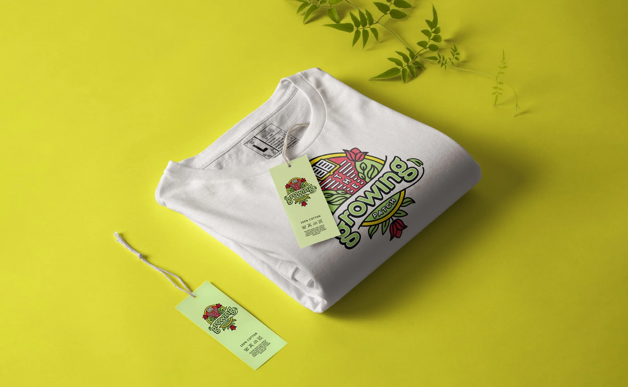 Folded white t-shirt with The Growing Patch logo and matching hang tags on a yellow-green background