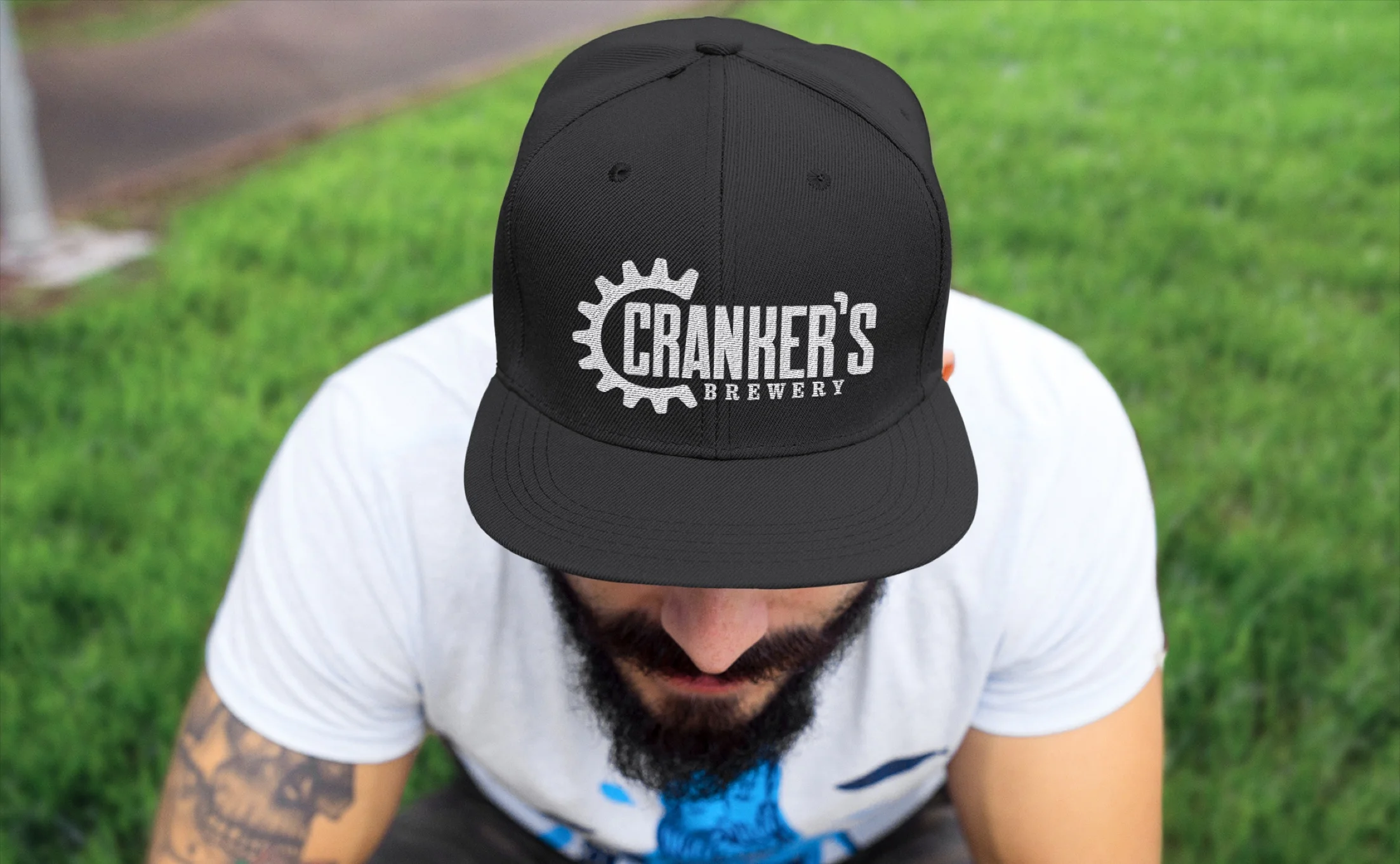 Man wearing a black snapback cap embroidered with the Cranker's Brewery logo