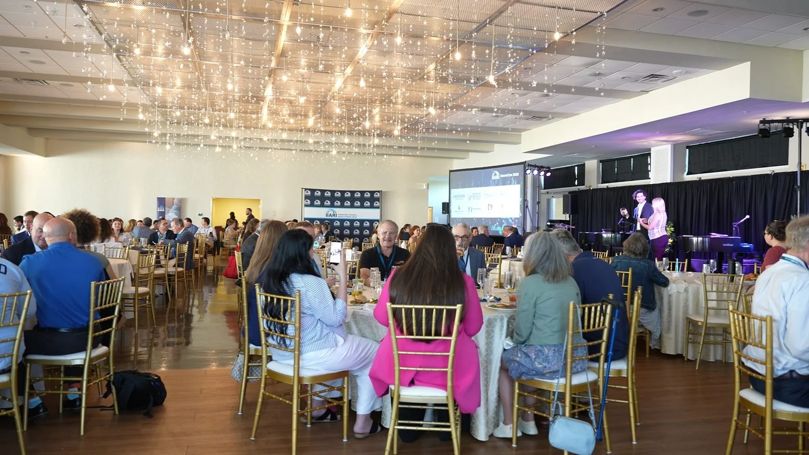 Ben Travelyn performing a stage magic show for a full room at a conference ballroom