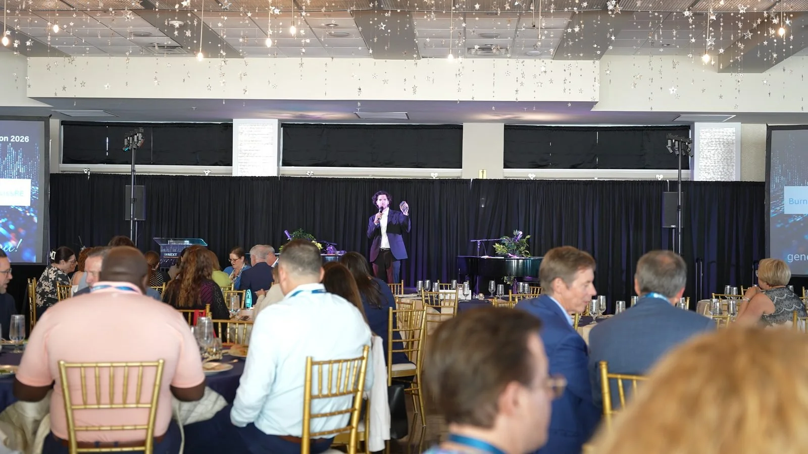 Ben Travelyn performing a stage show for a seated corporate audience at an awards dinner