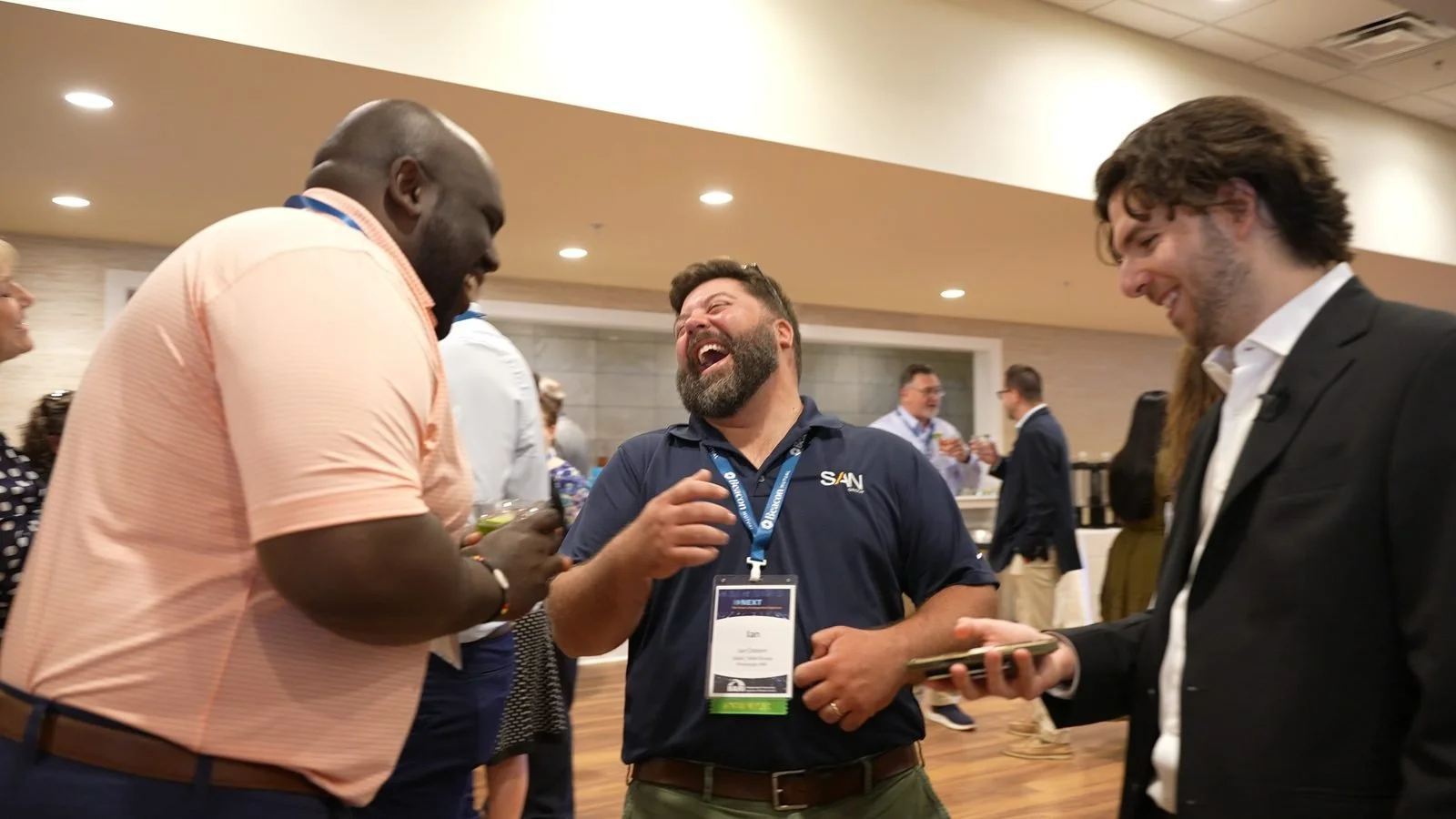 Conference attendees laughing during a close-up magic performance at a networking reception