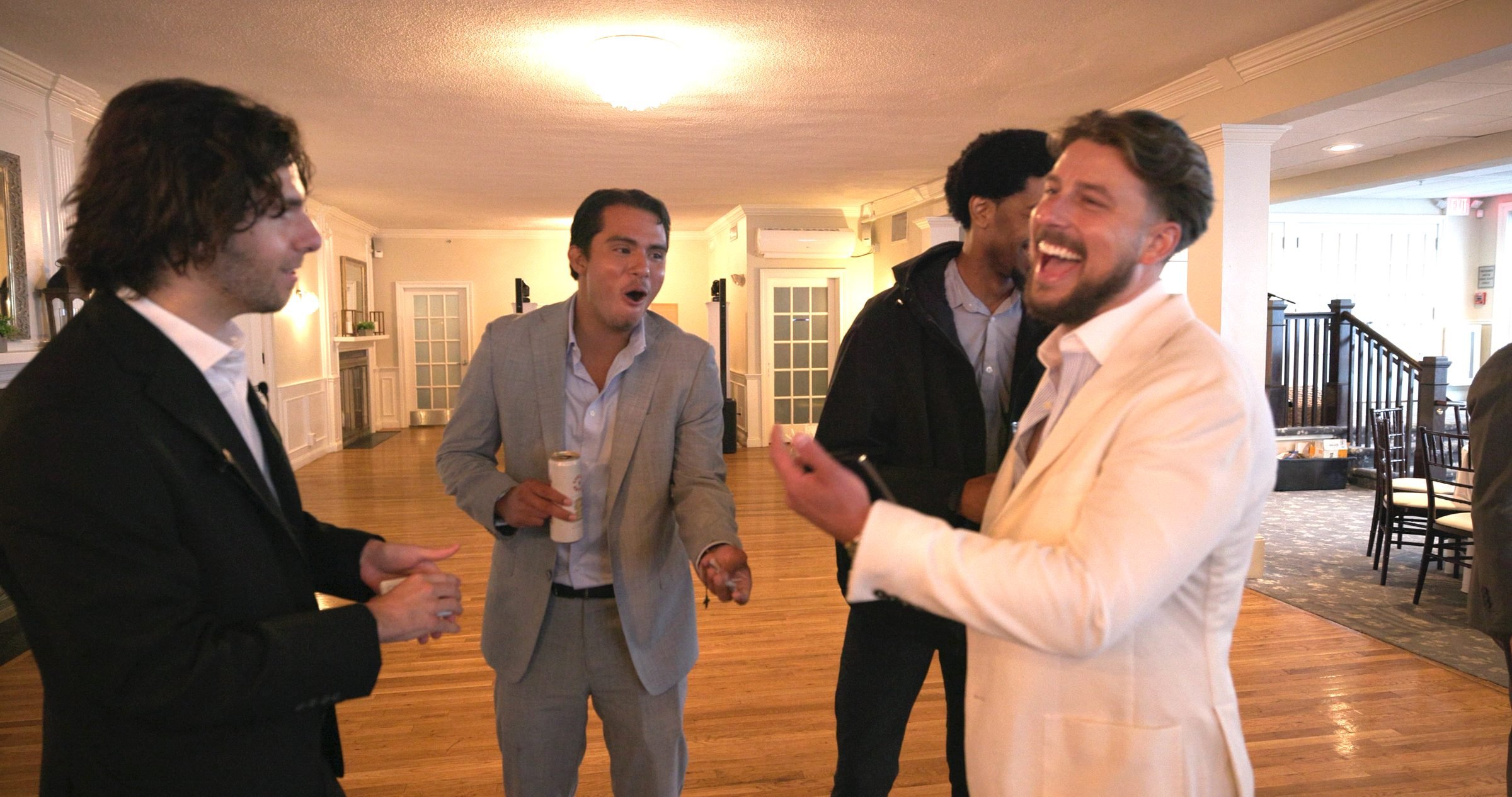 Groomsmen laughing during close-up magic at a Rhode Island wedding reception