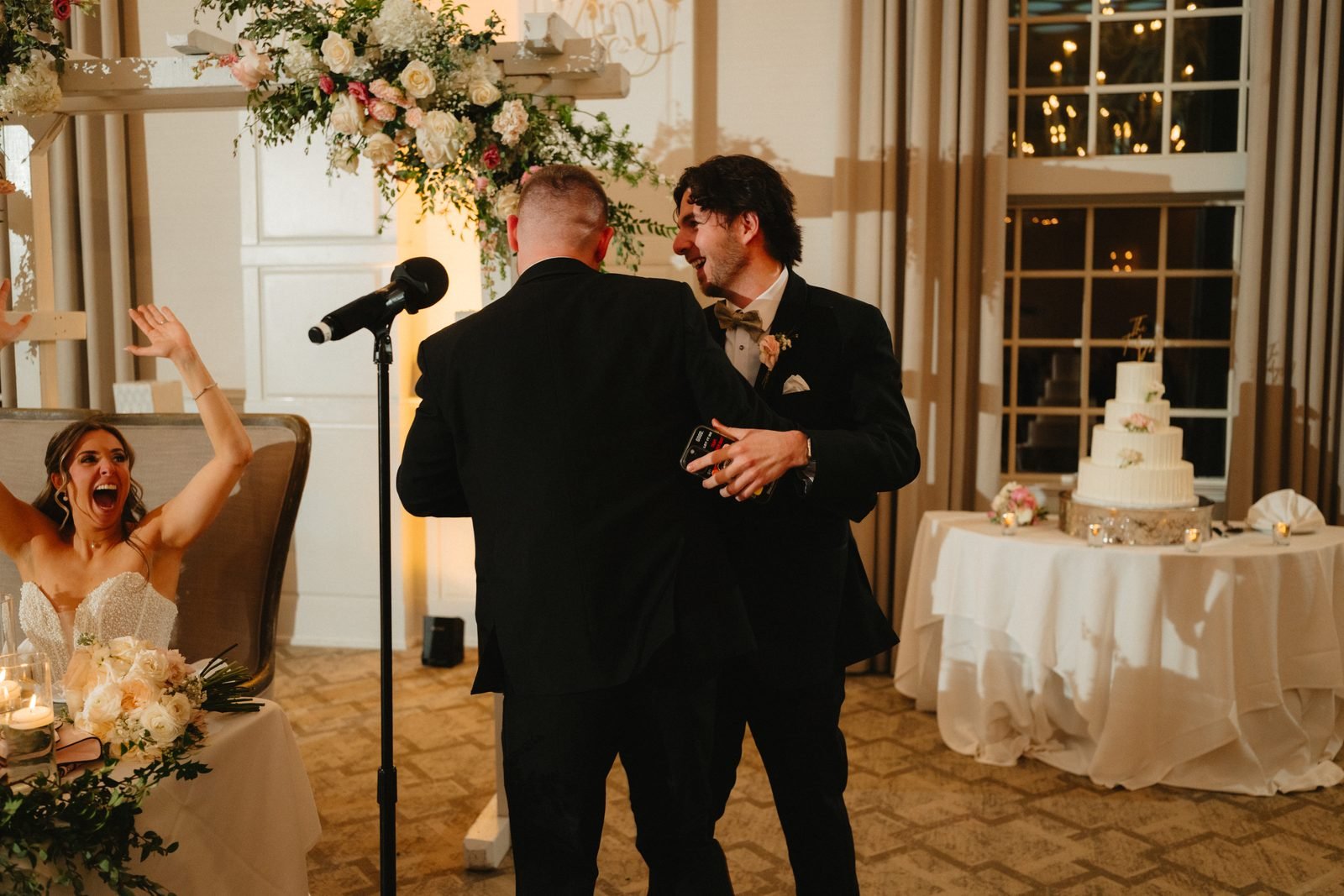 Wedding magician performing during a reception as the bride cheers from the head table in Worcester, Massachusetts