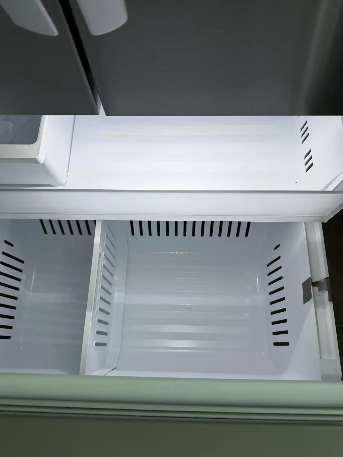 The same empty freezer drawer with the visible crumbs and debris removed
