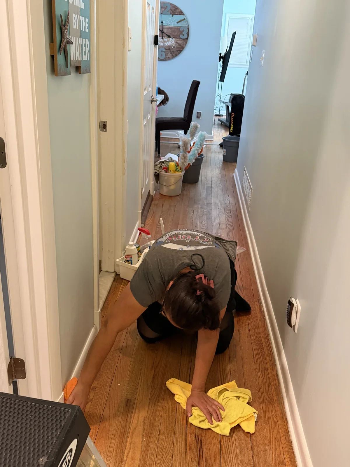 Prime Cleaning team member cleaning along a hallway floor and baseboard
