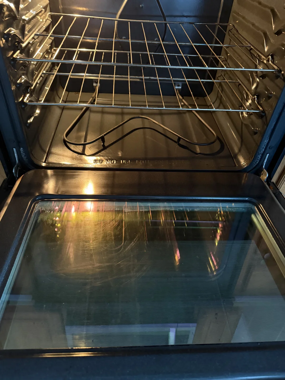 The same electric oven with a cleaner bottom, racks and door glass after cleaning