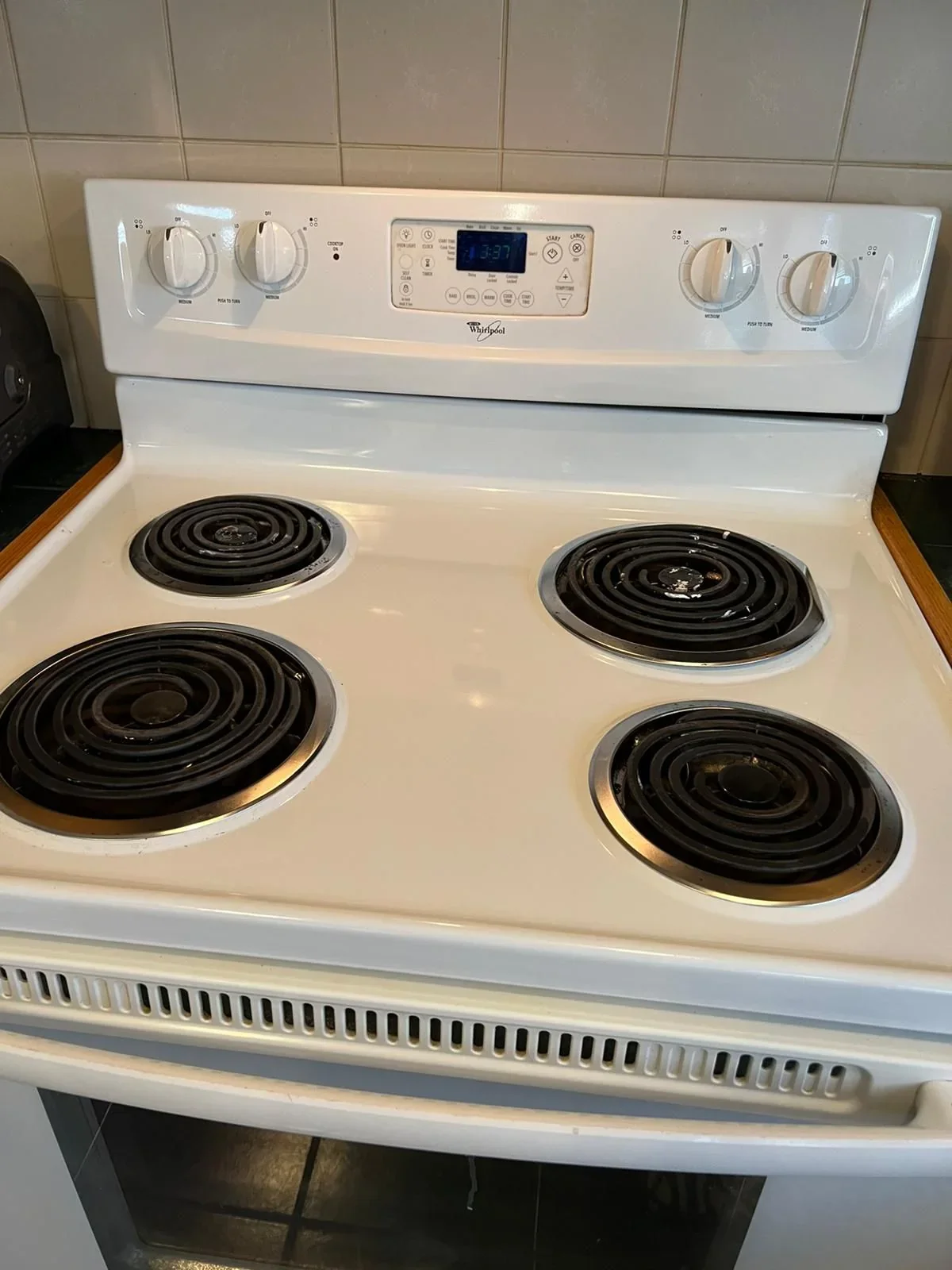 The same white electric stovetop with visibly cleaner surfaces around the coil burners