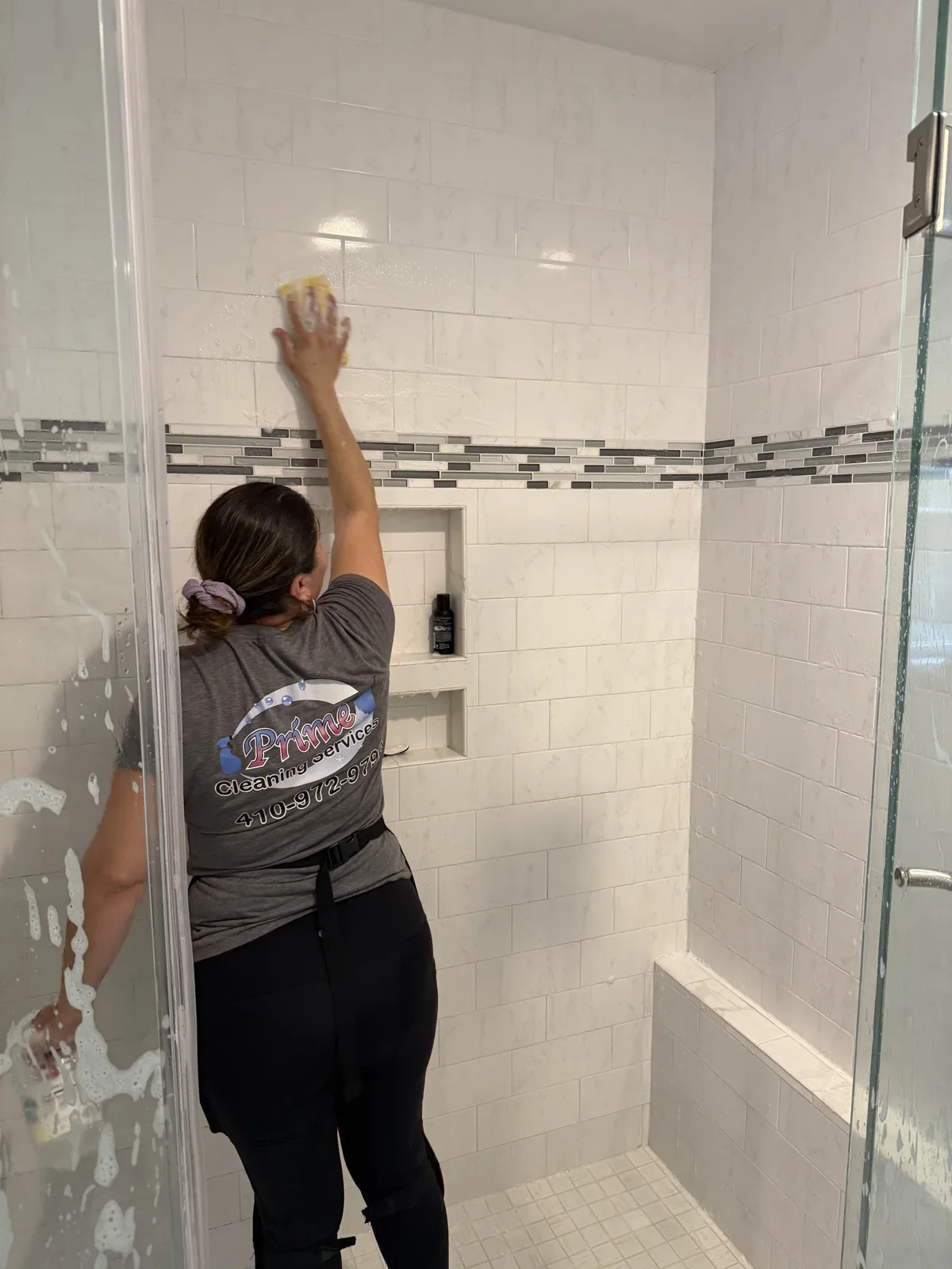 Prime Cleaning team member wiping tile inside a shower