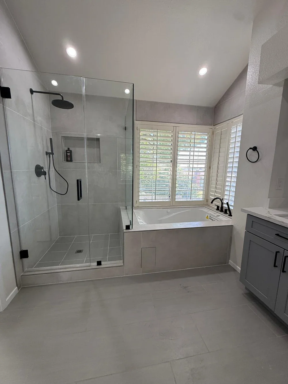 Bathroom with frameless glass shower, a soaking tub, large tile and matte black fixtures
